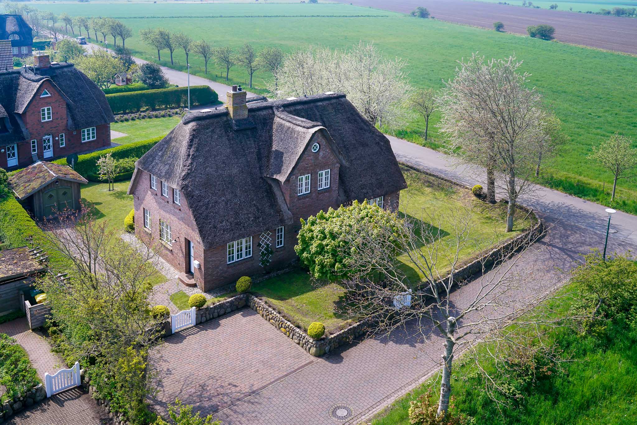 Das Landhaus zwischen blühenden Bäumen und frühlingsgrünen Feldern